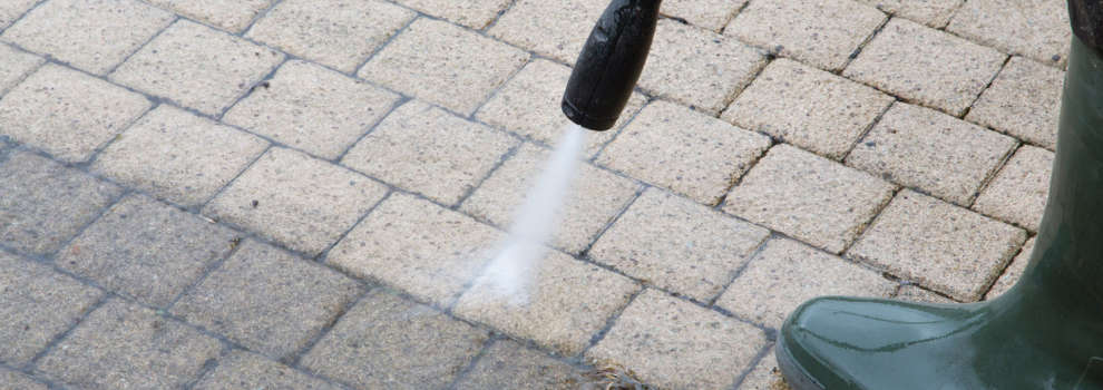 power washing away grime from brick pavers