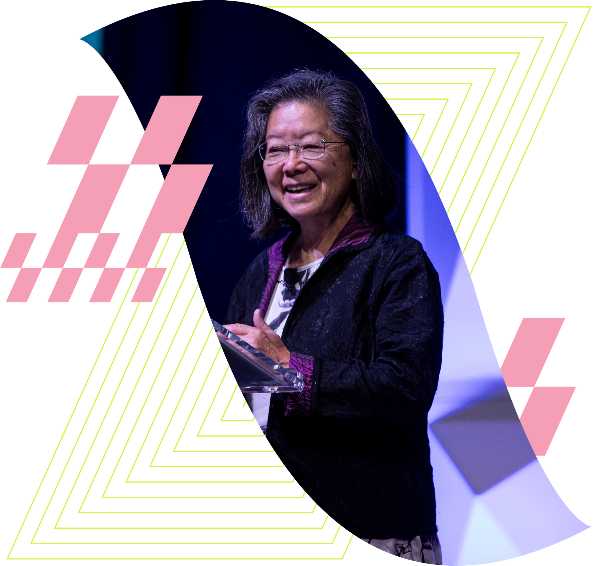 Smiling speaker on stage with a purple backdrop and geometric pink-and-yellow design accents