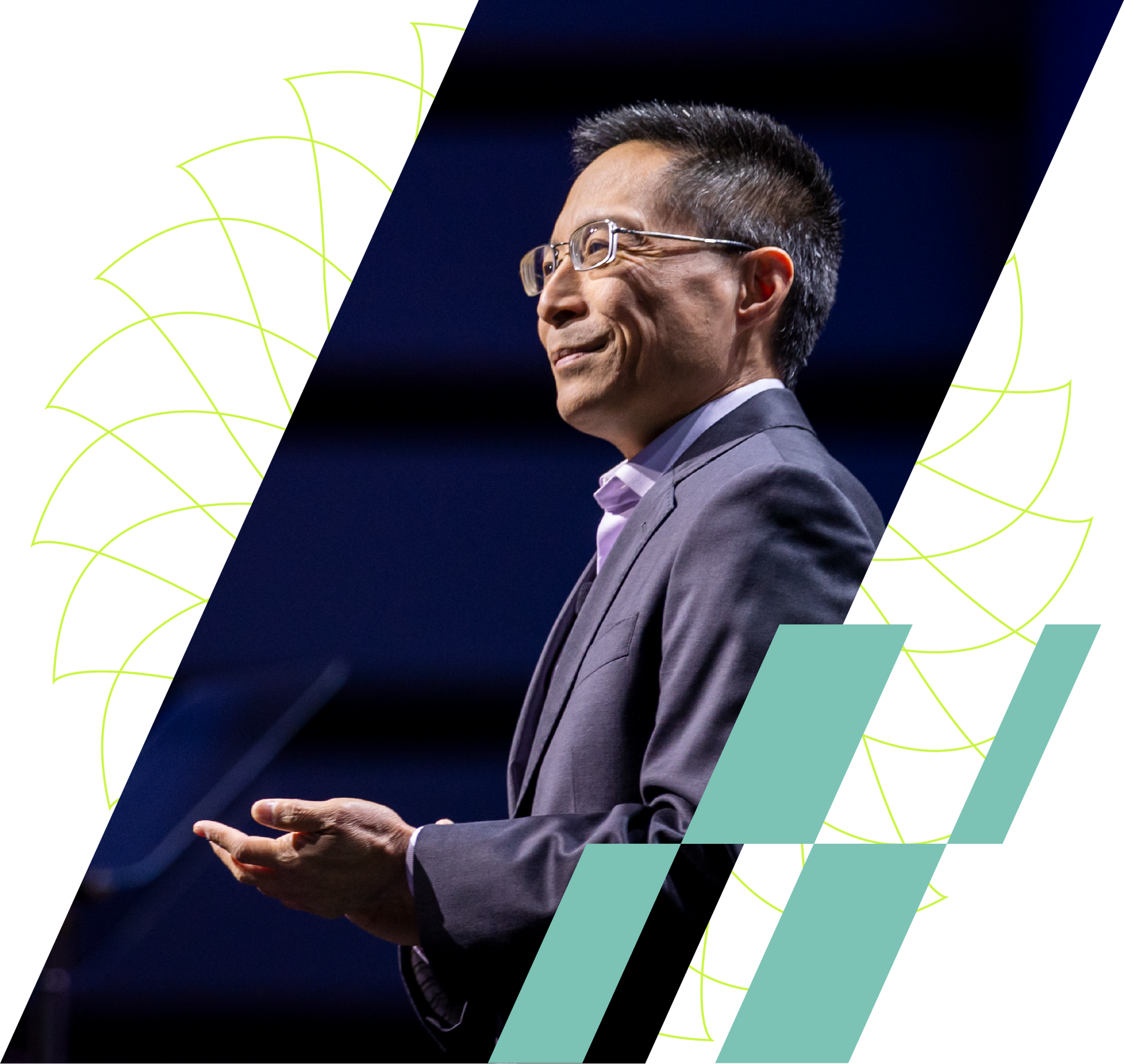 Man speaking on stage in a purple suit, lit against a dark background with geometric teal accents.