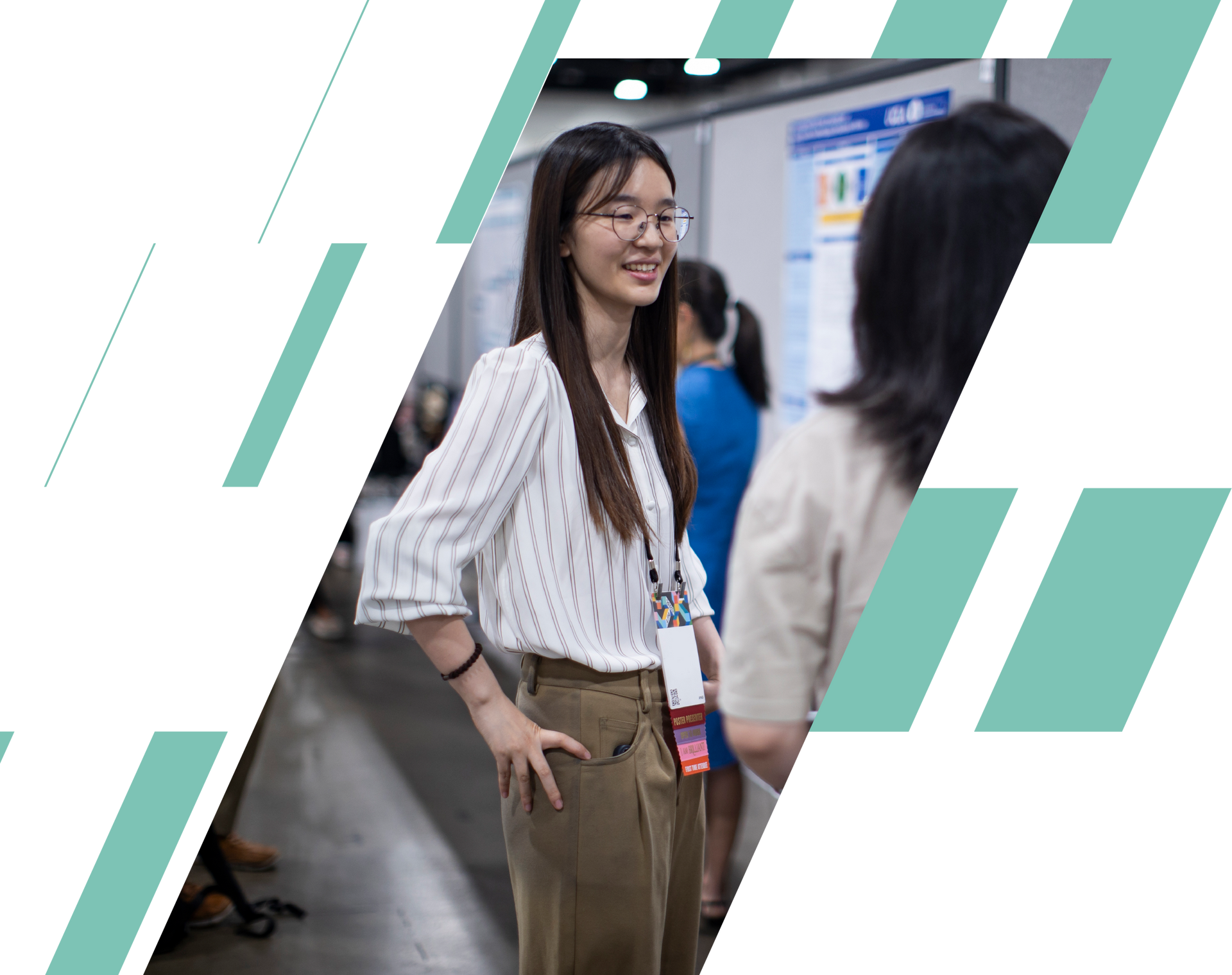 Two people talking at a conference, one smiling in a striped shirt with a lanyard.