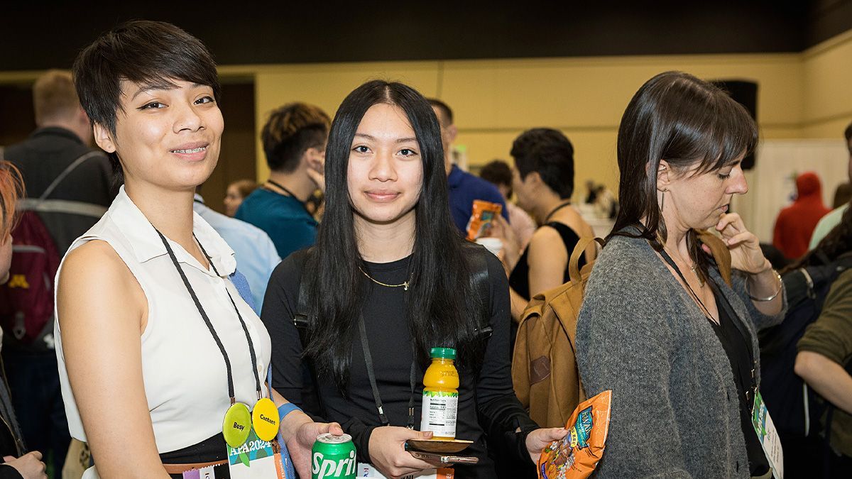 Three women are standing next to each other in a crowded room.