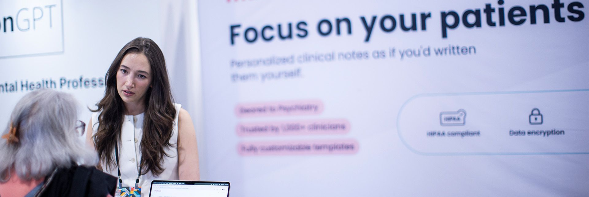 Woman presenting at a conference beside a slide reading “Focus on your patients”