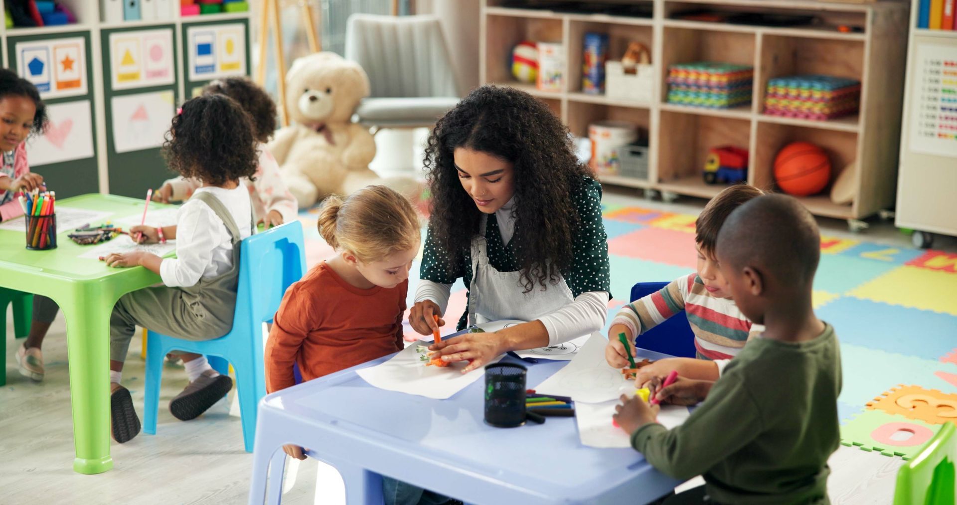 A group of children are sitting at desks with a teacher