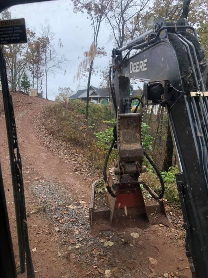 A deere excavator is sitting on top of a dirt road.