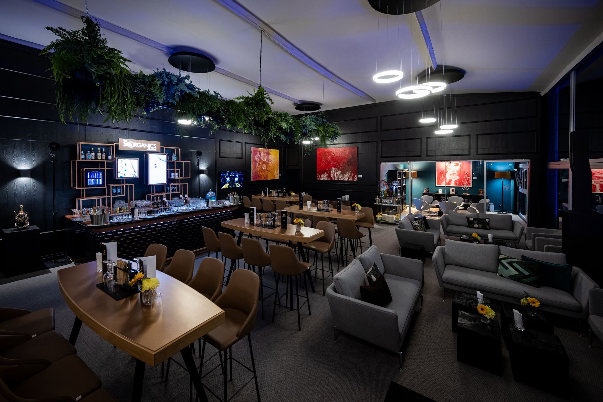 Ein großer Raum mit Tischen, Stühlen, einer Couch und einer Bar.