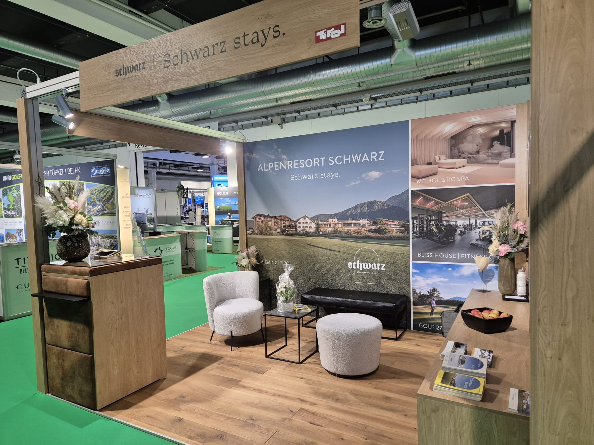 Ein Messestand mit Stühlen, Ottomanen und einem Tisch.