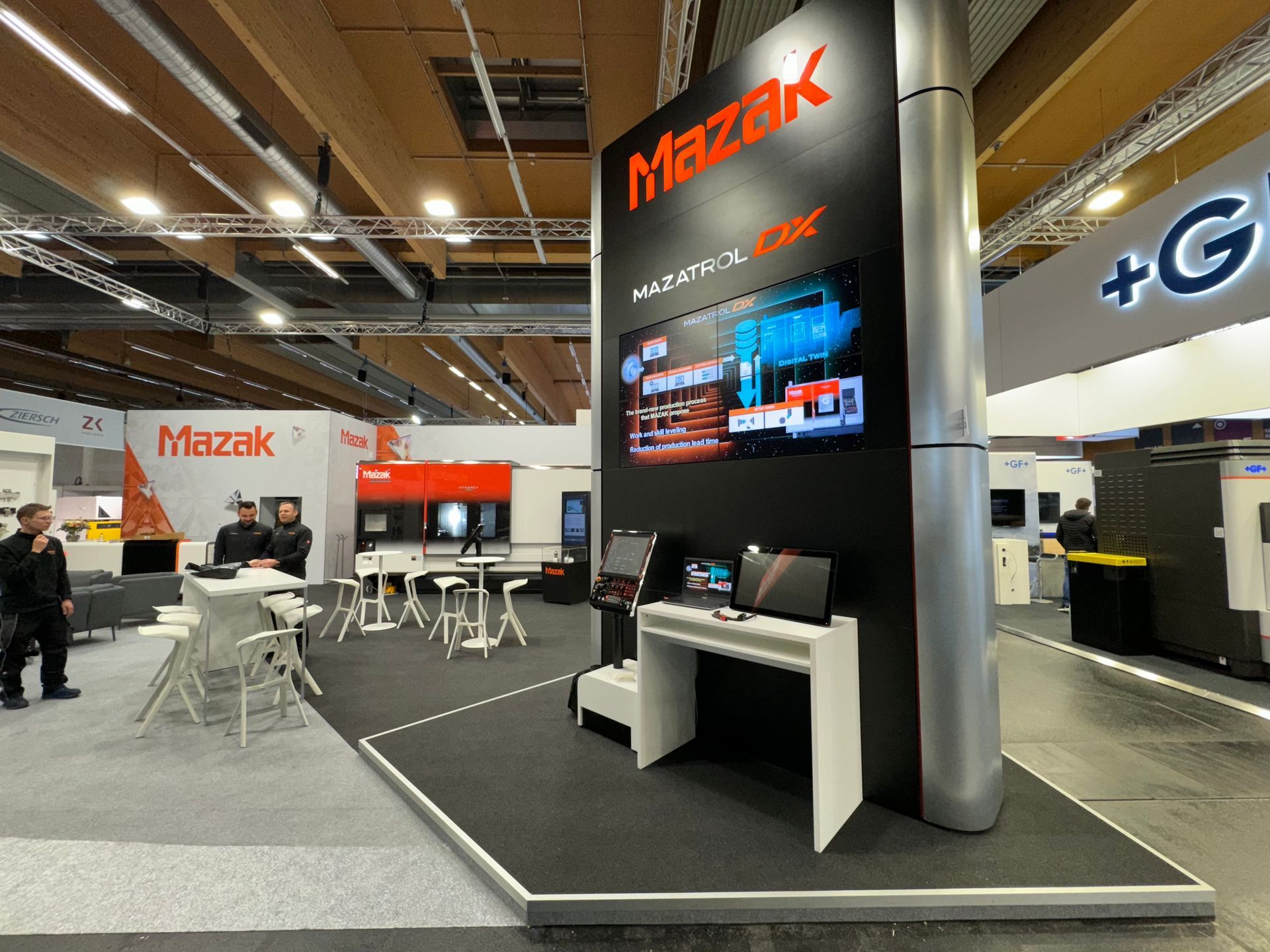 Ein Mazak-Stand auf einer Messe mit Tischen und Stühlen