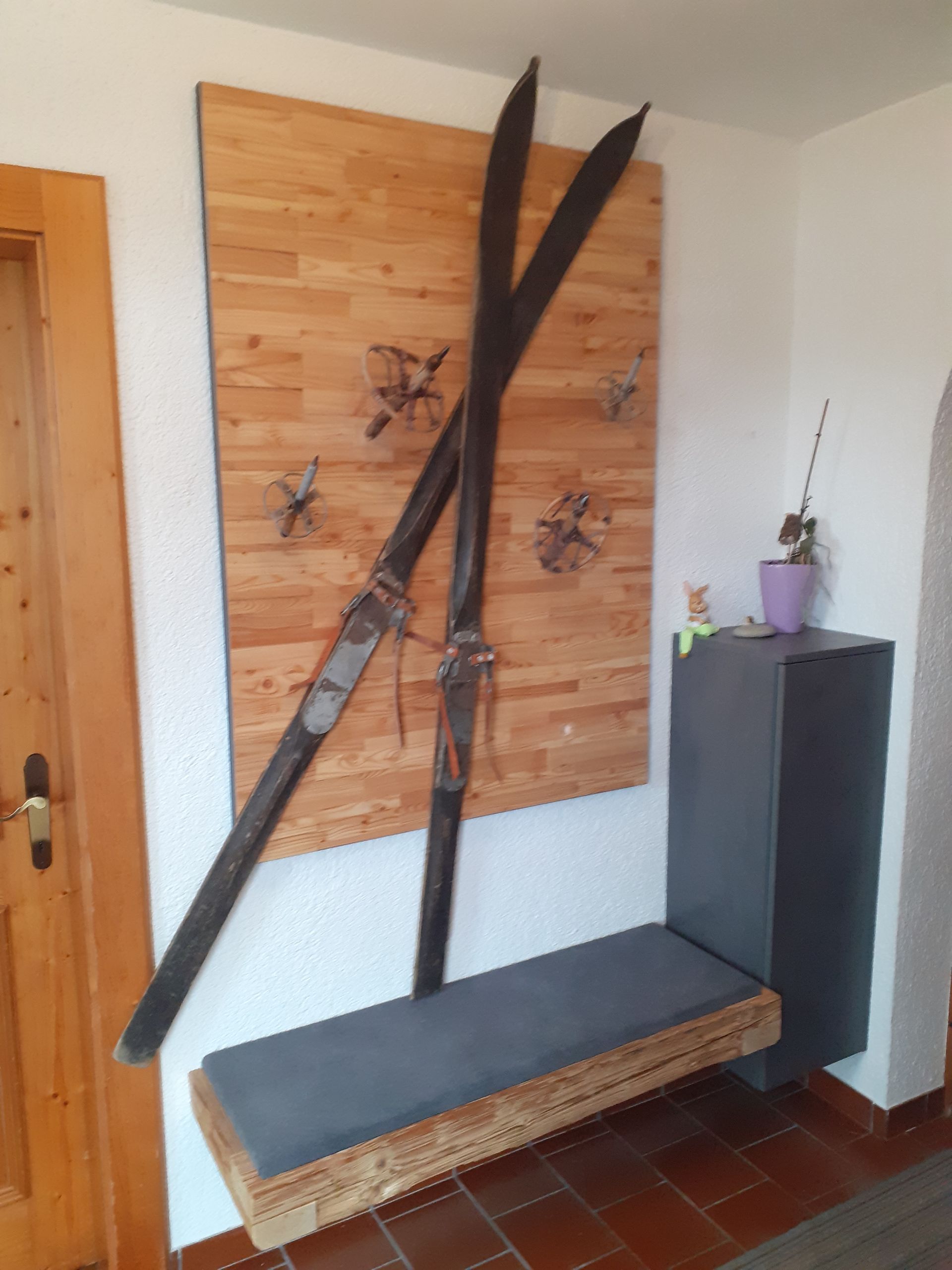 Zwei Skier hängen an einer Holzwand über einer Bank