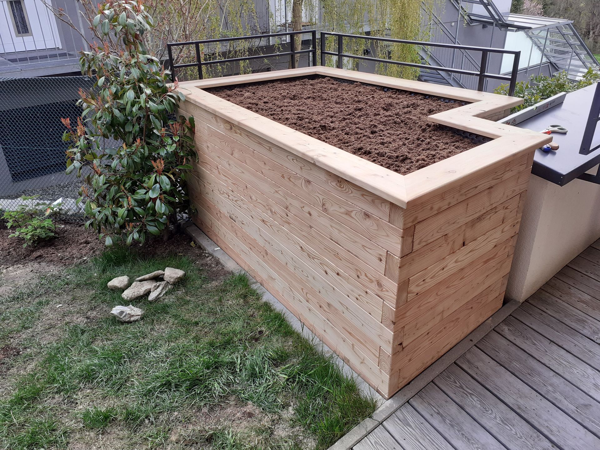 Auf einem üppigen grünen Rasen steht ein Blumentopf aus Holz.