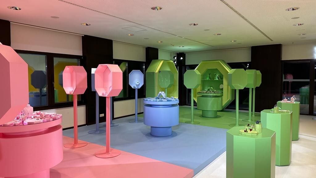 Ein Raum voller rosa und grüner Tische und Ausstellungsstücke.
