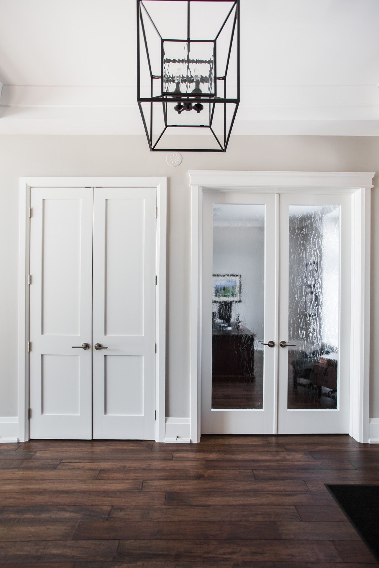 A hallway with white doors and a chandelier hanging from the ceiling.
