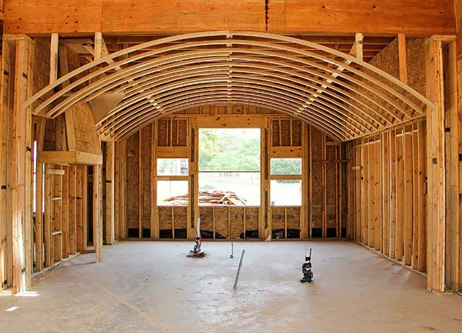 The inside of a building under construction with wooden beams and a window.