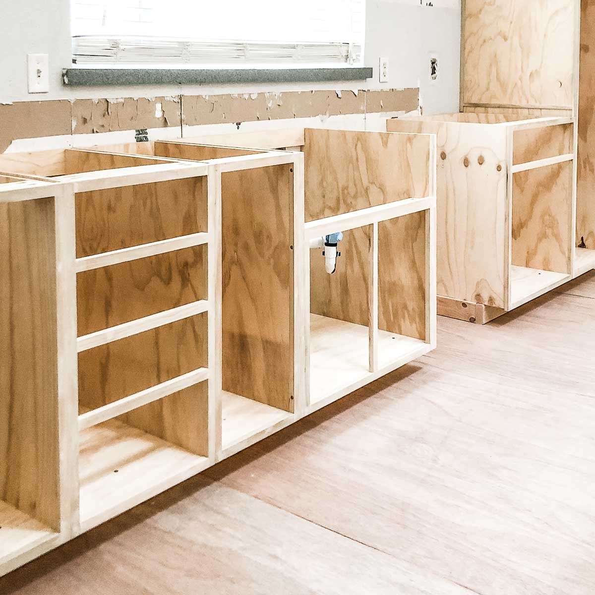 A row of wooden cabinets are being built in a kitchen.