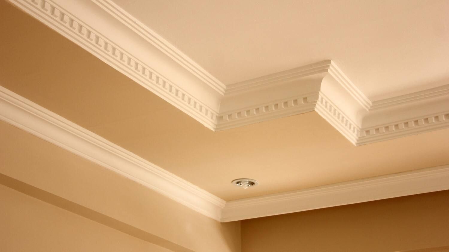 A close up of a ceiling with crown molding in a room.
