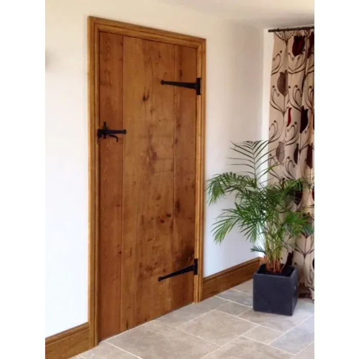 A wooden door in a hallway next to a potted plant