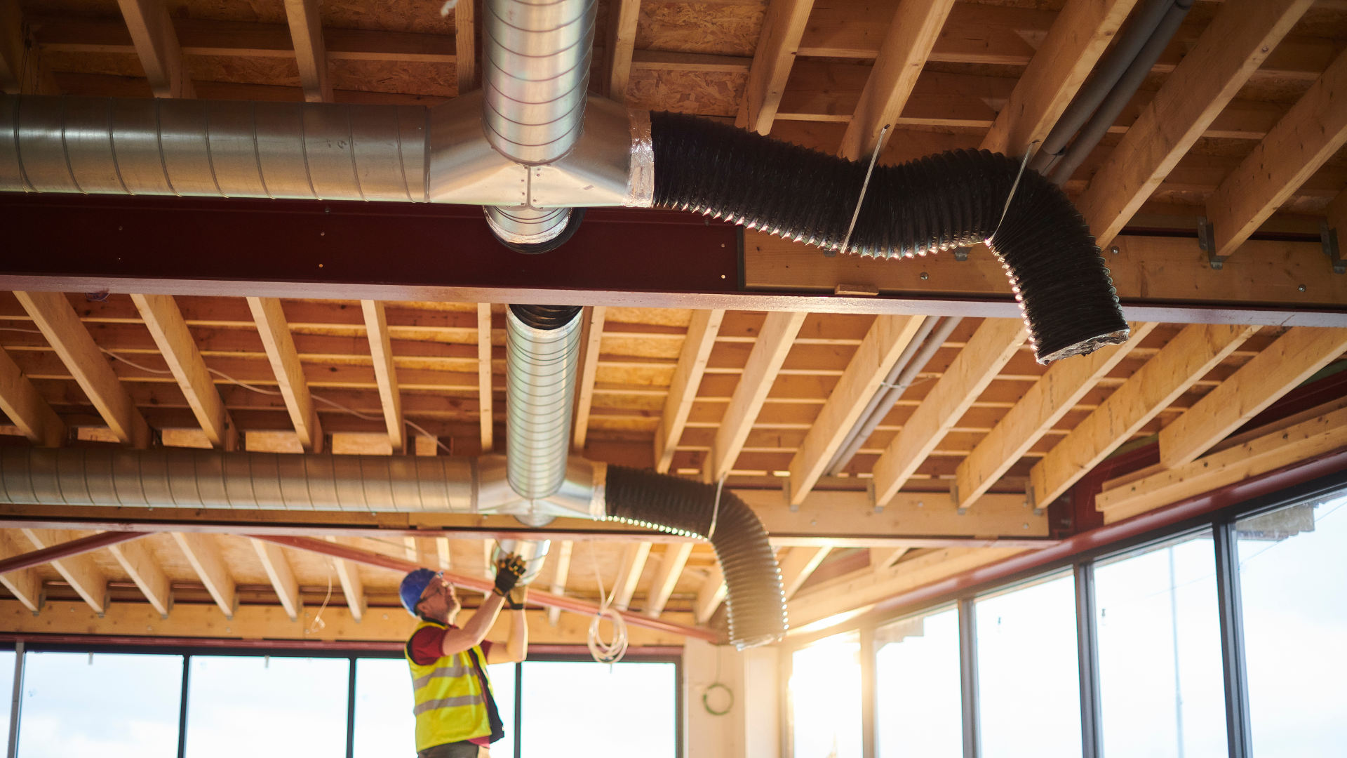 A construction worker is working on the ceiling of a building.