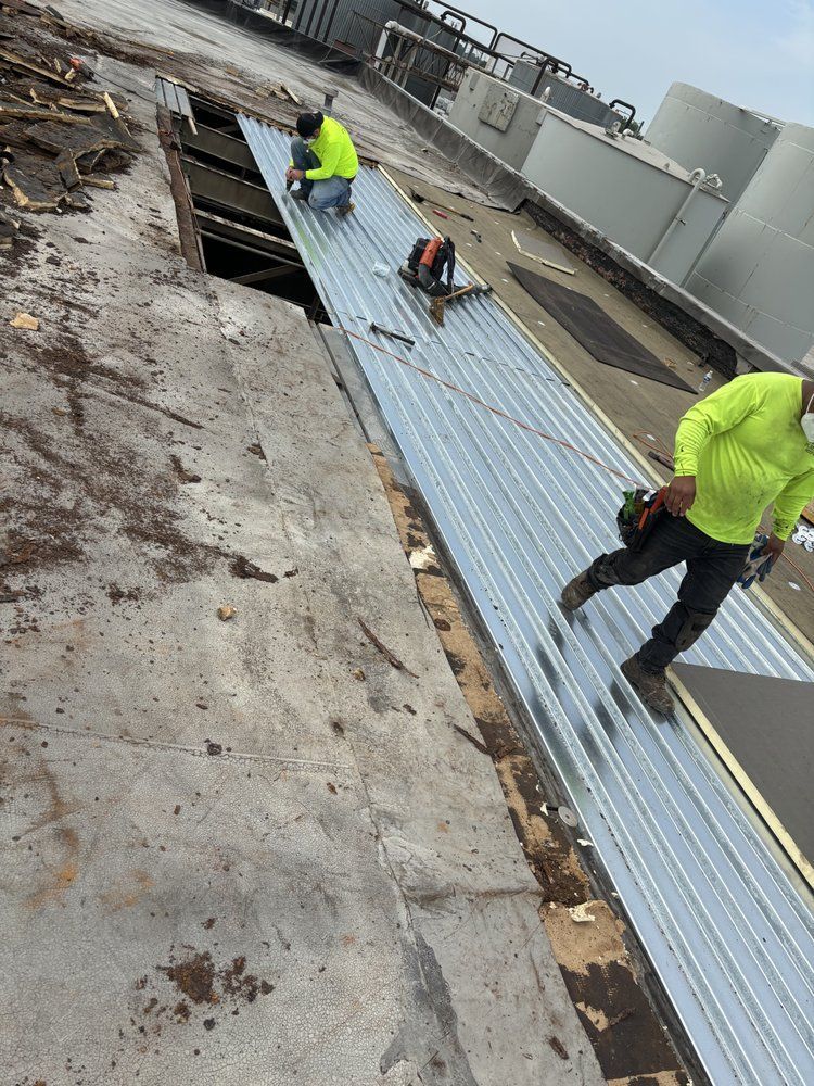 Two men are working on a metal roof.