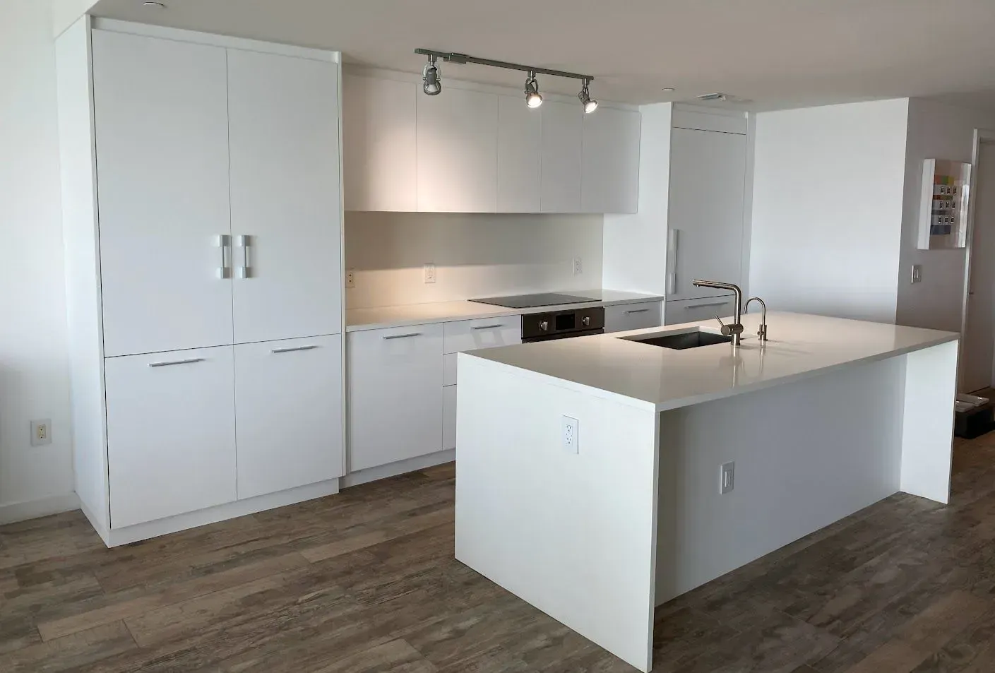 A kitchen with white cabinets and a large island in the middle.