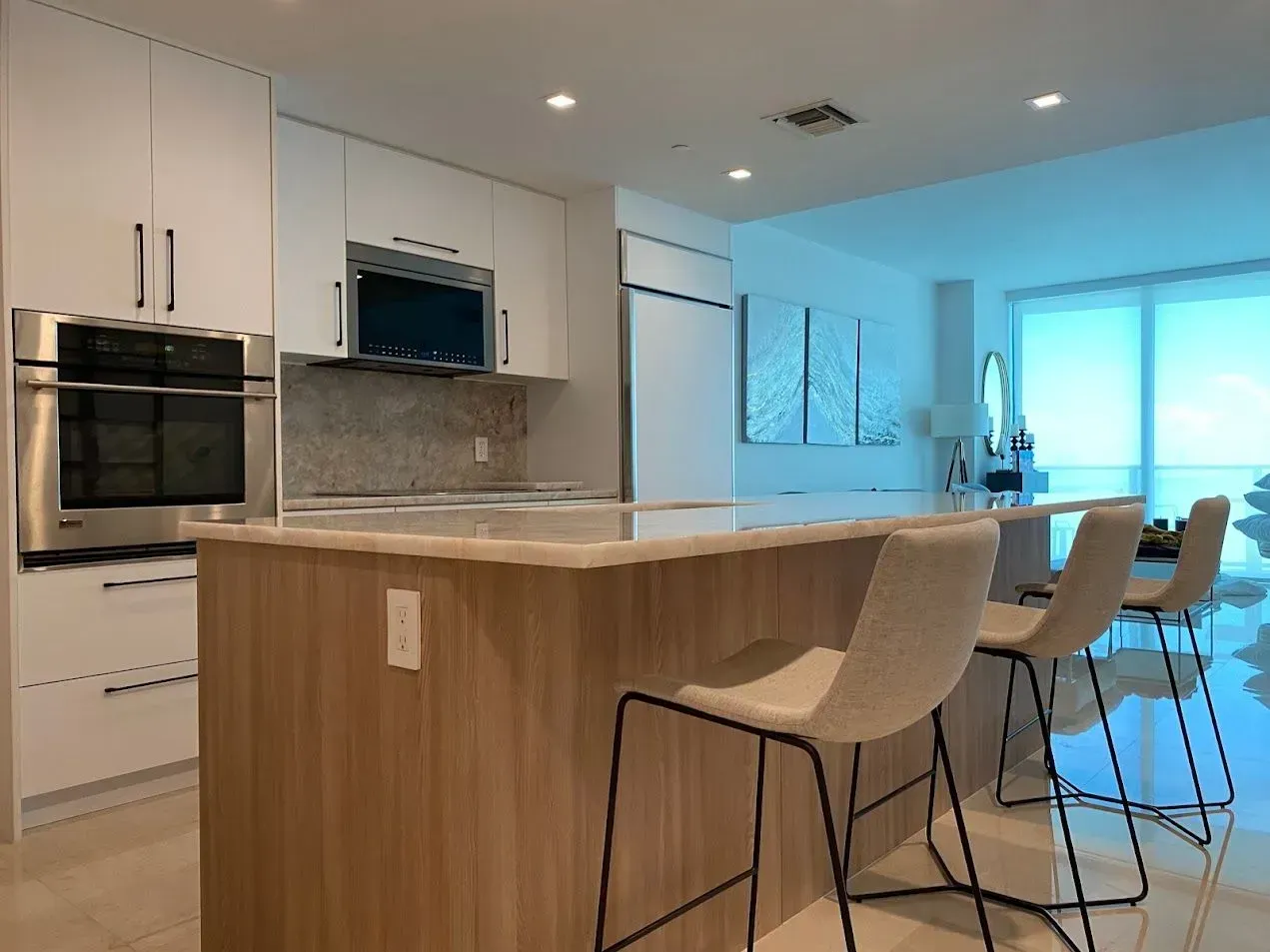 A kitchen with white cabinets , stainless steel appliances and a large island.
