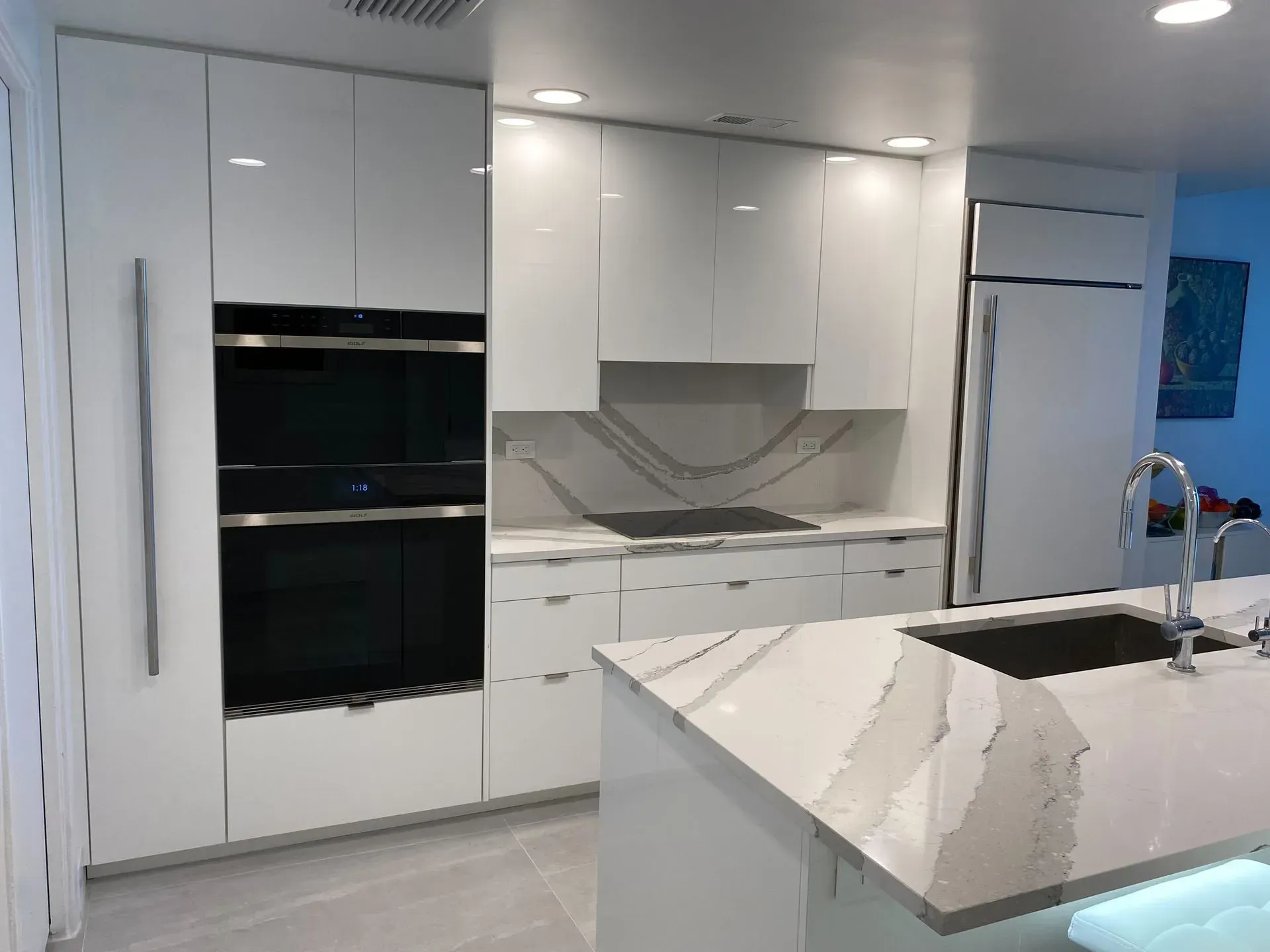 A kitchen with white cabinets , stainless steel appliances and a large island.