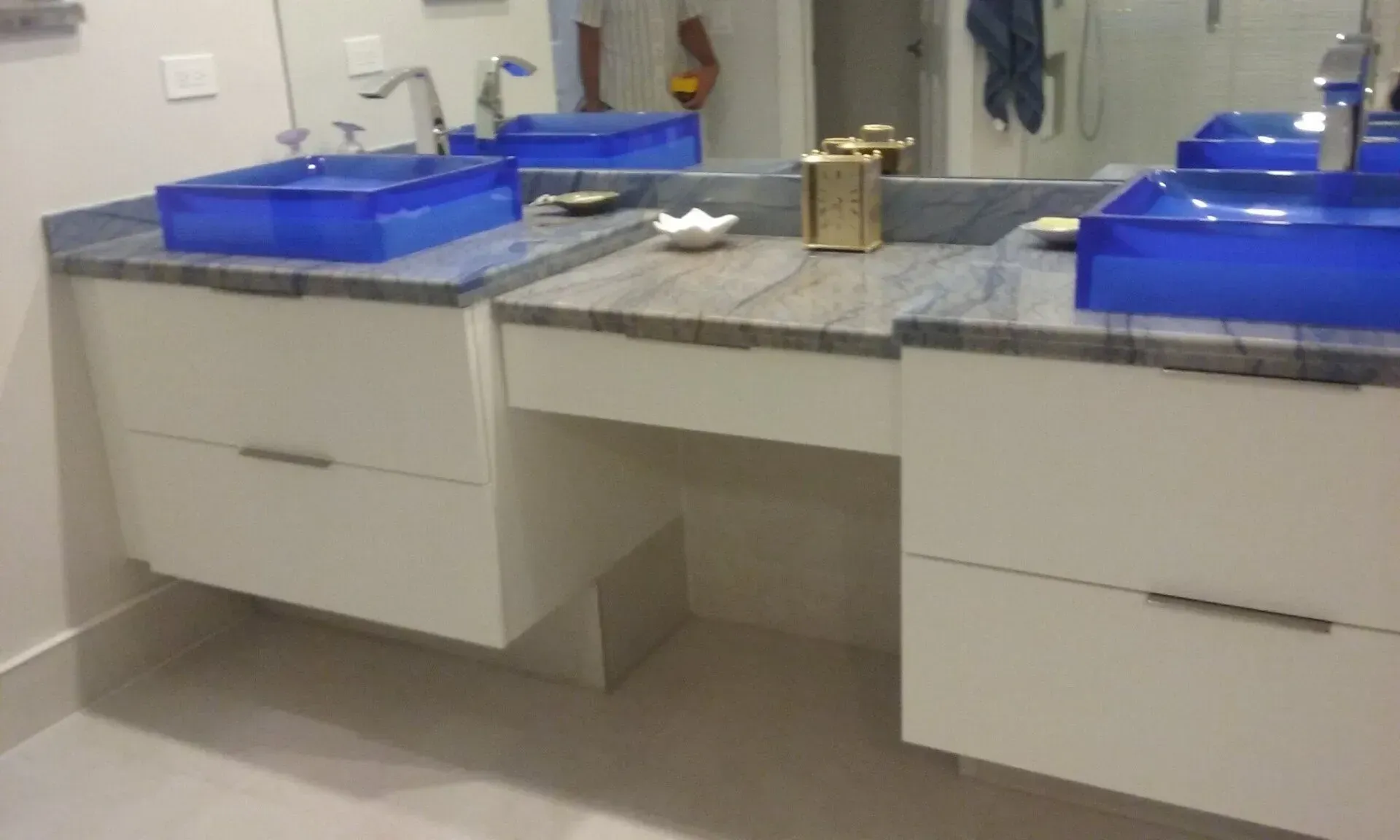 A bathroom with two blue sinks and a mirror.