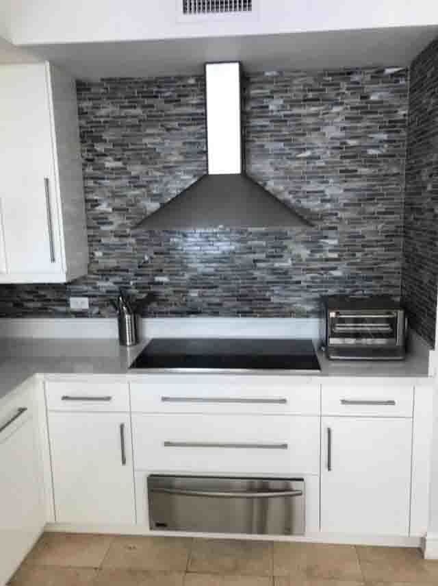 A kitchen with white cabinets , a stove top oven , and a toaster oven.