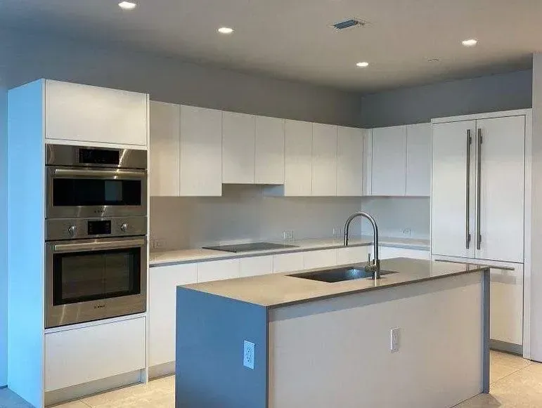 A kitchen with white cabinets , stainless steel appliances and a large island.