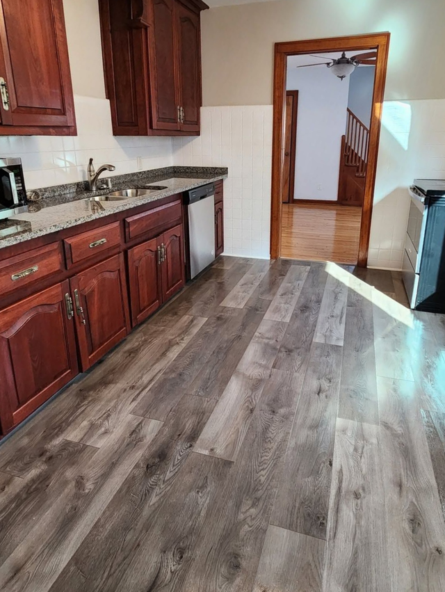 Kitchen with dark wood cabinets, gray flooring, and an open doorway to a hallway.