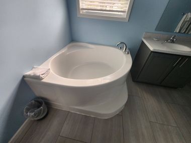 Small bathroom with a corner bidet beside a dark vanity and window