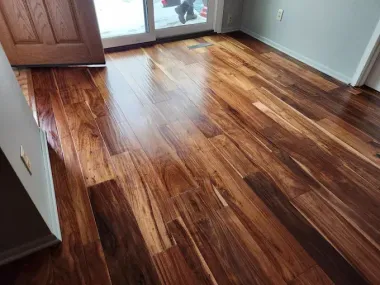 Empty room with glossy wood floor and sliding glass door letting in sunlight