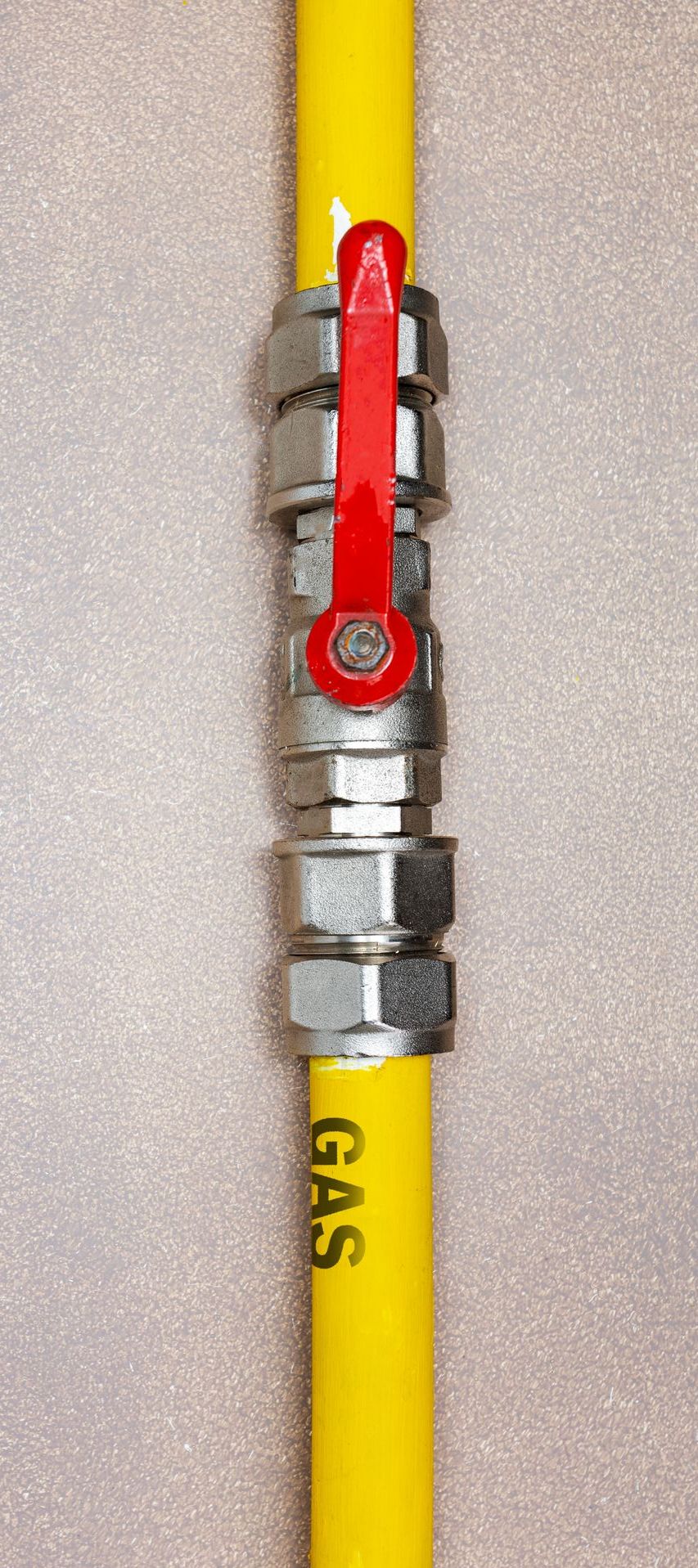 A yellow gas pipe with a red valve attached to it.