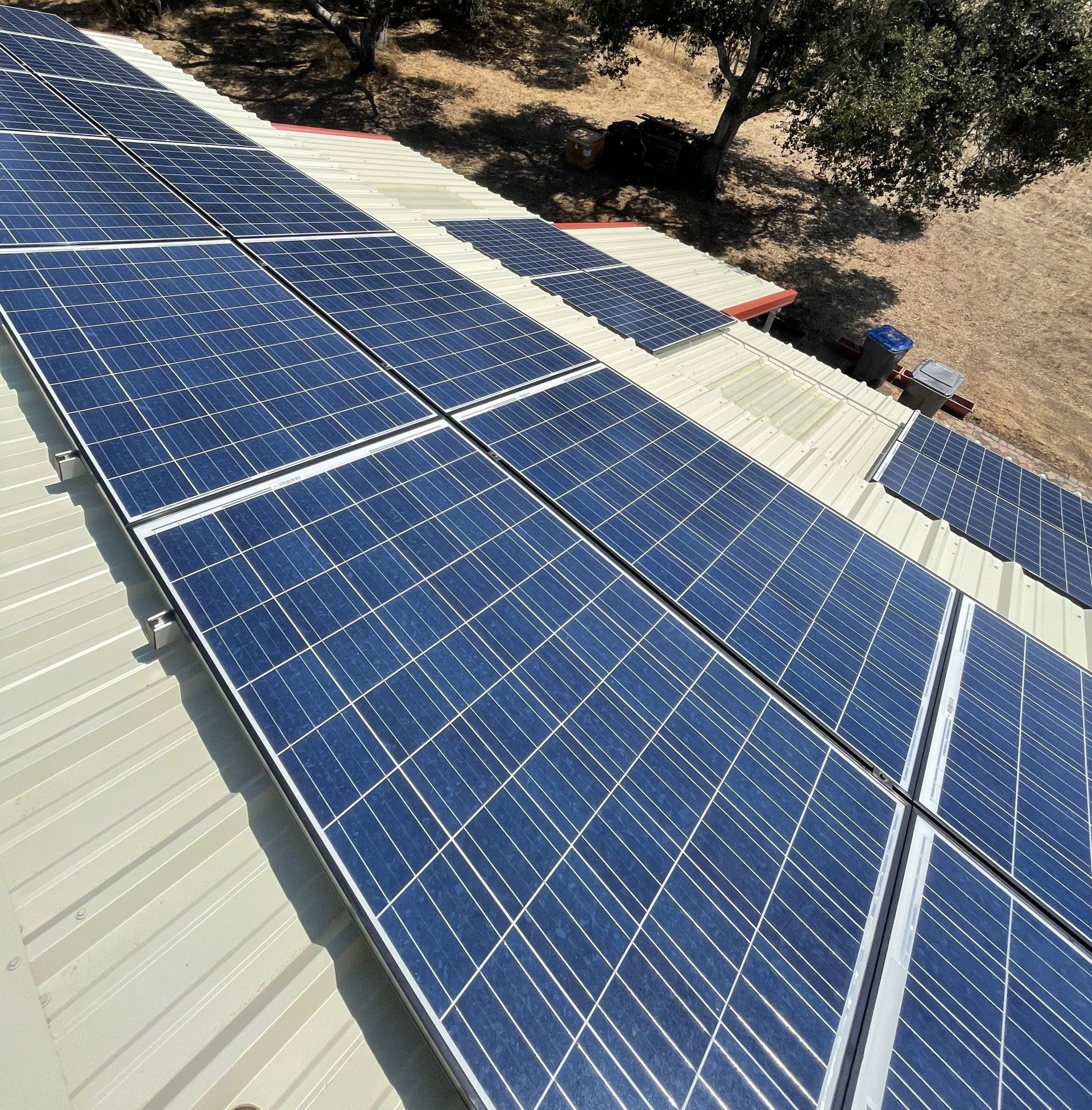 A row of solar panels on a roof with trees in the background