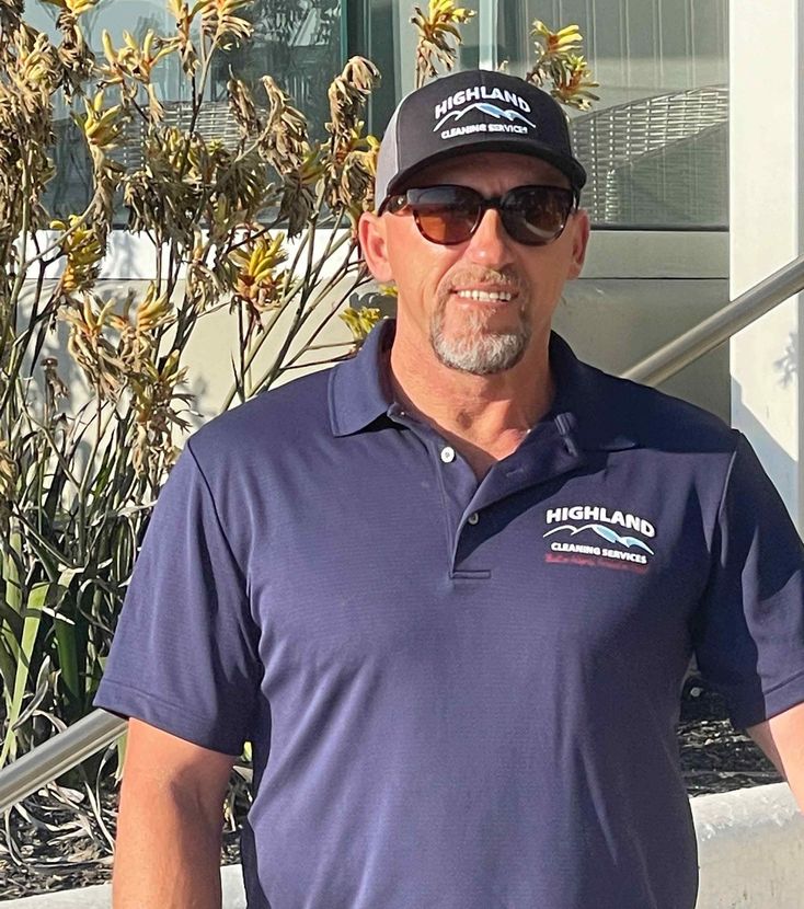 A man wearing a hat and sunglasses is standing in front of a building.