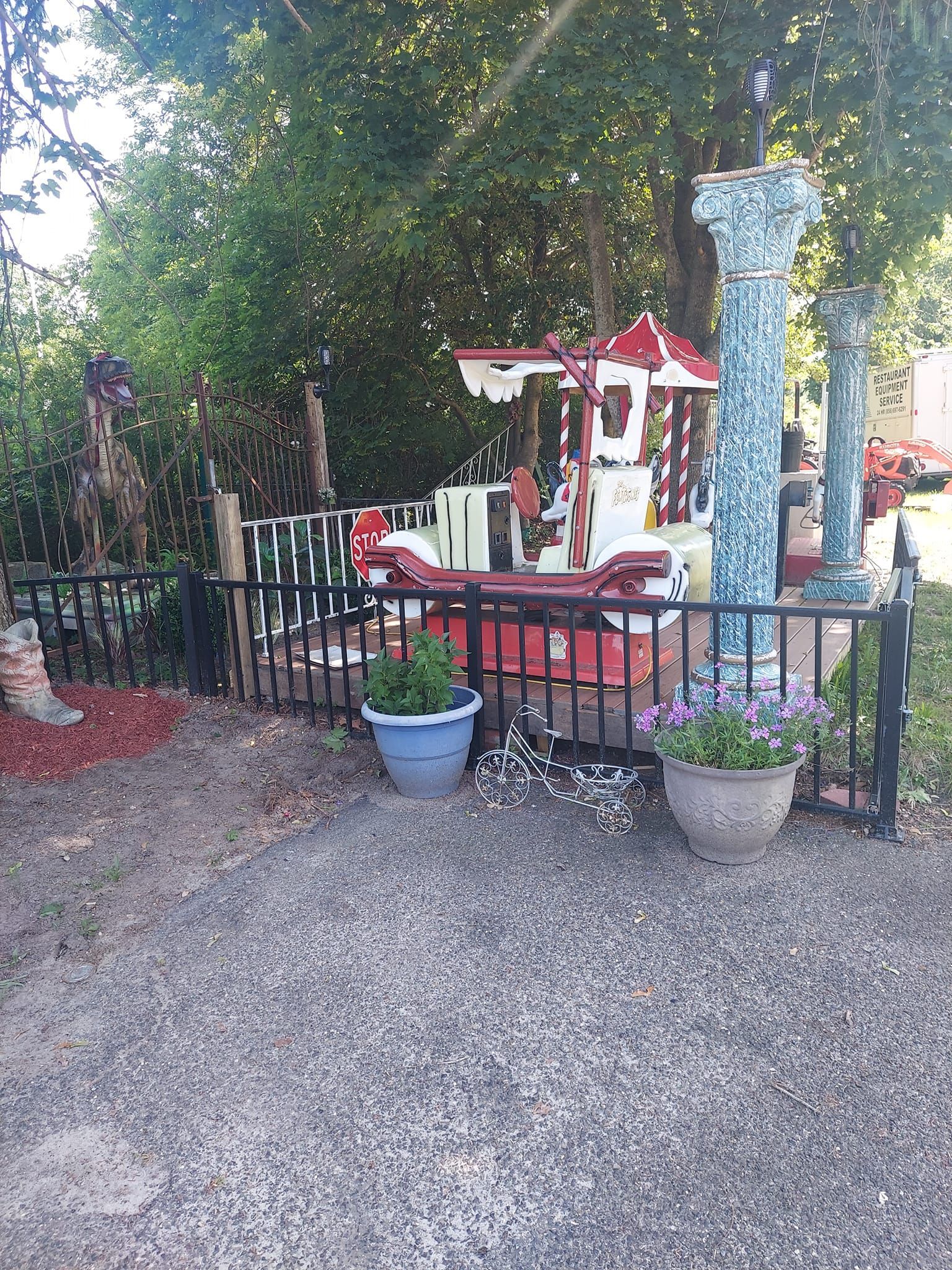 A carousel is behind a fence with potted plants in front of it.