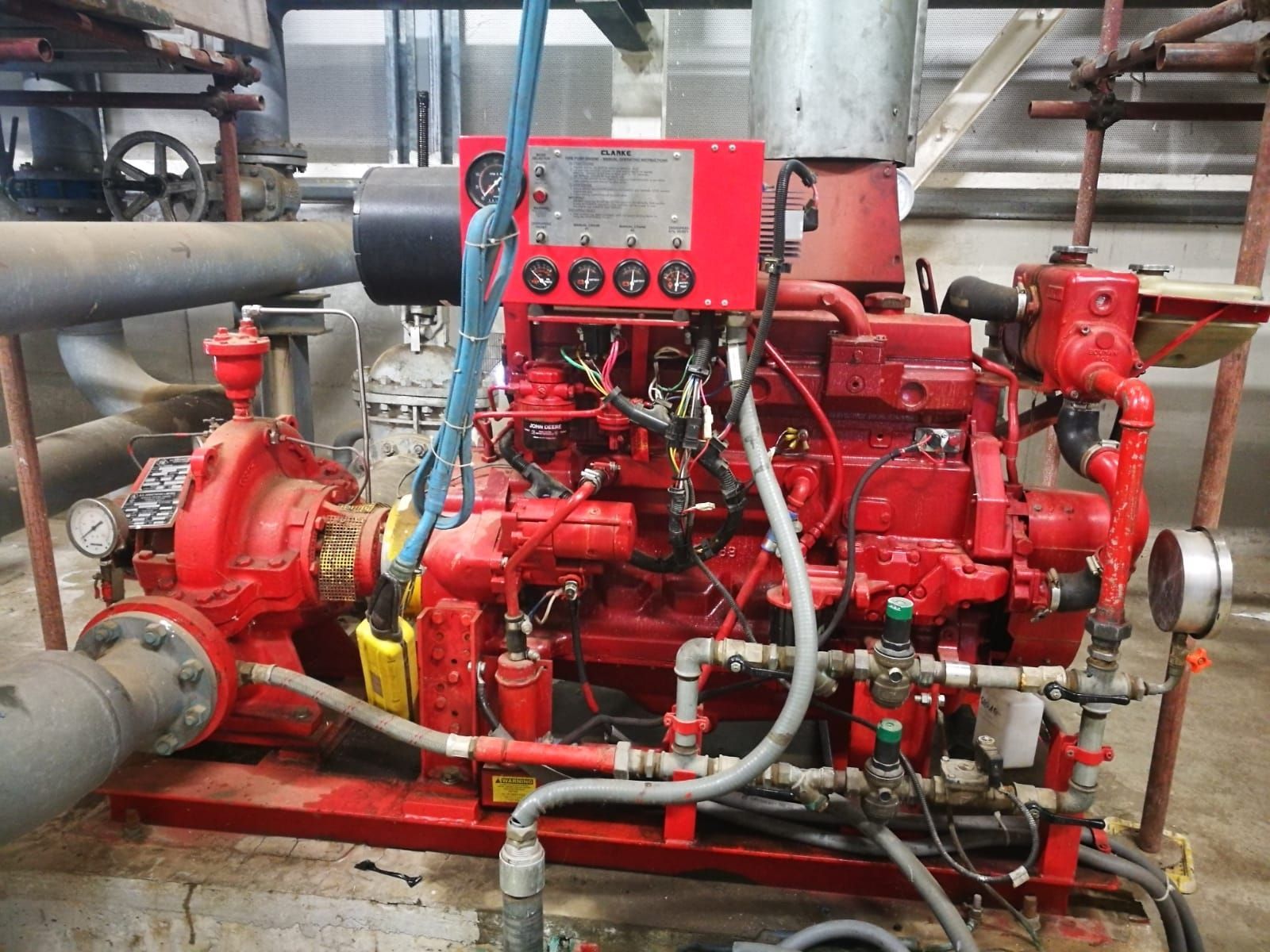 Un motore rosso è parcheggiato in una stanza circondata da tubi.