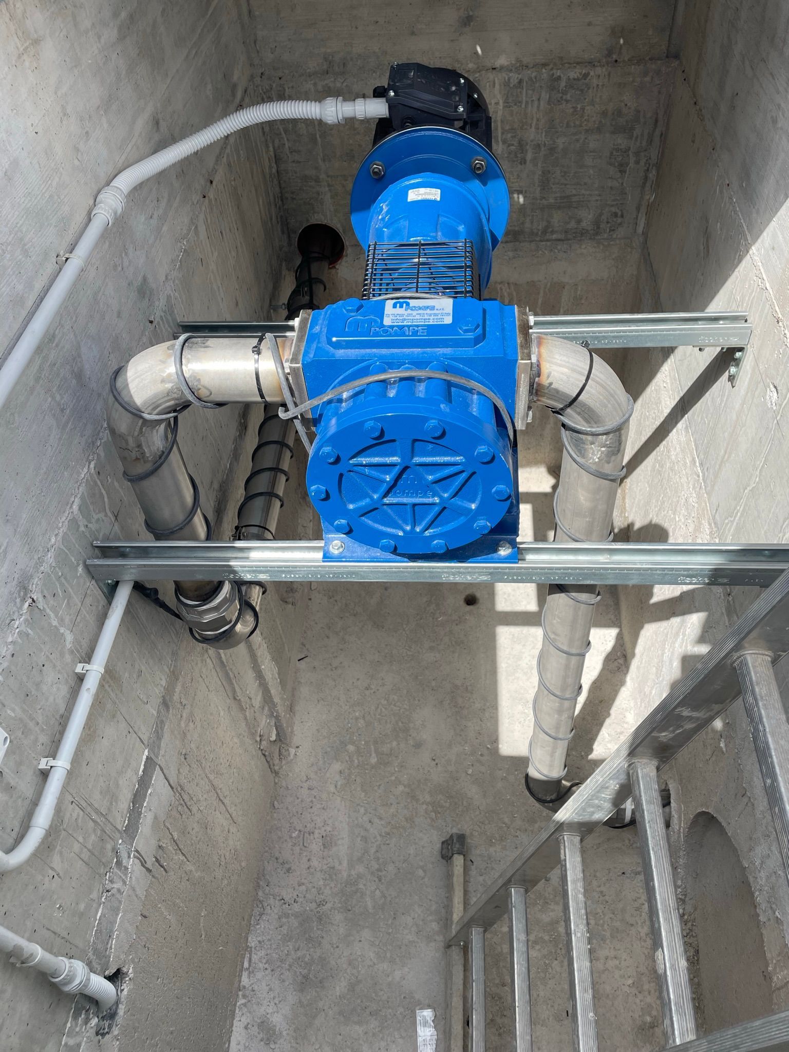 Una pompa blu è posizionata in una stanza di cemento accanto a una scala.