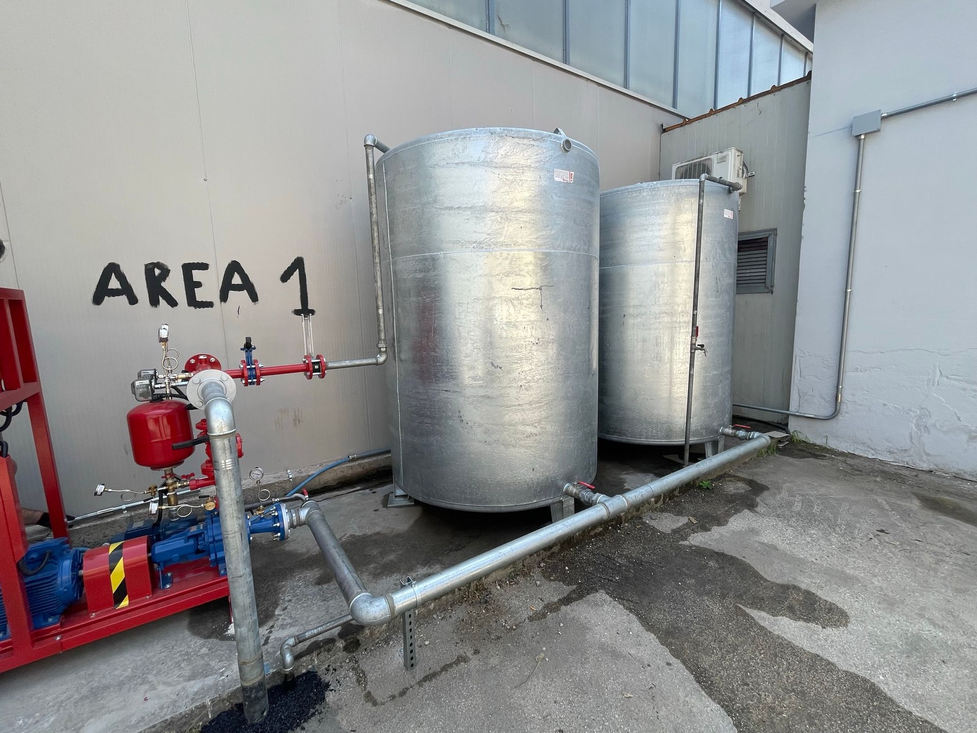 Due serbatoi metallici sono posizionati di fronte a un muro su cui è scritto 