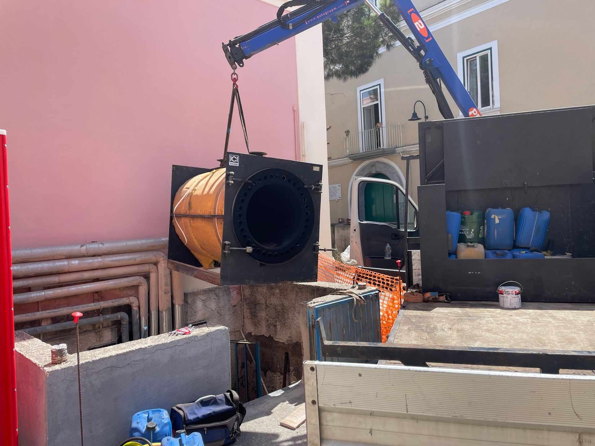 Una gru sta sollevando un oggetto di grandi dimensioni dal retro di un camion.