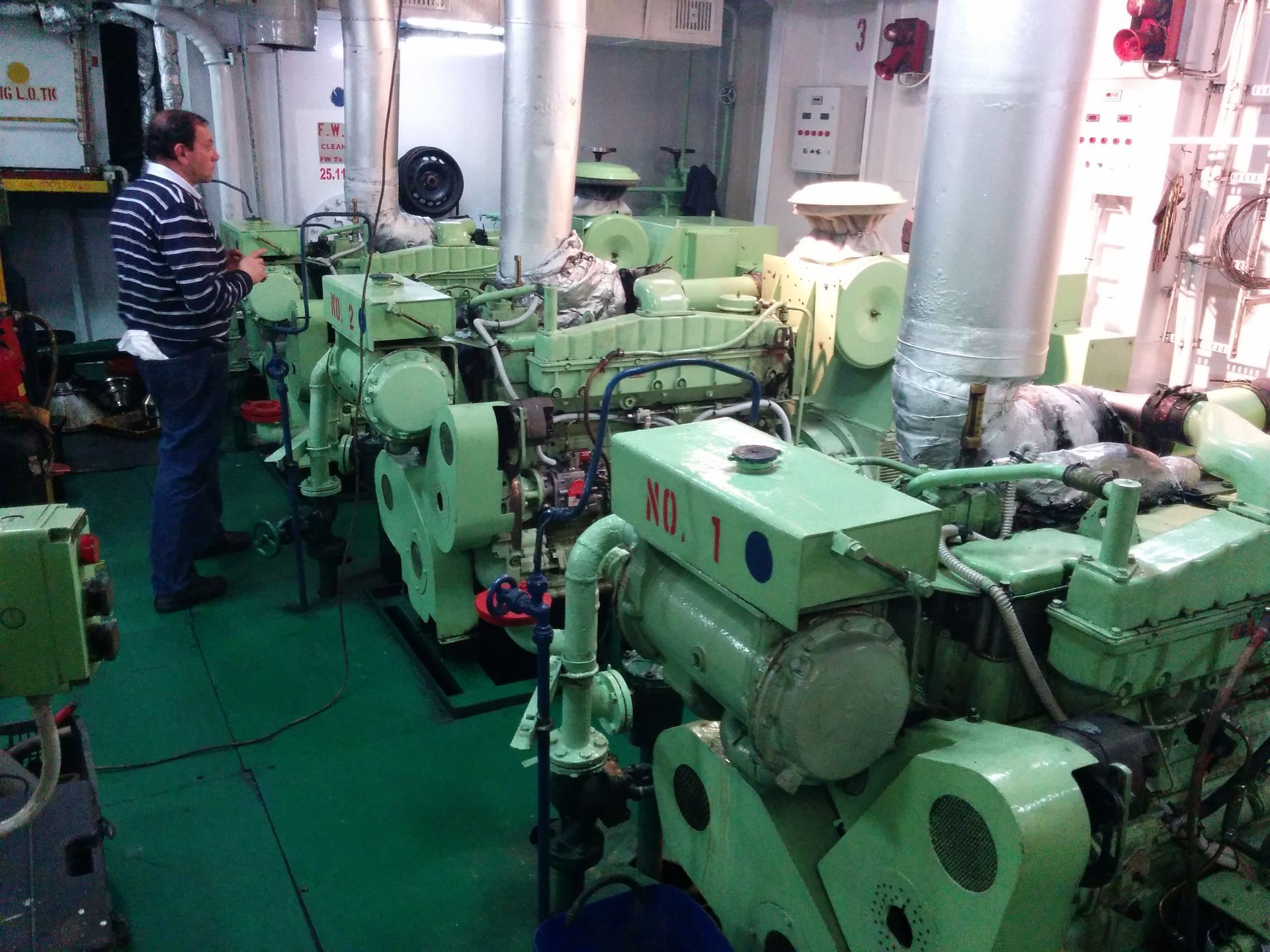 Un uomo è in piedi davanti a una fila di motori su una nave.