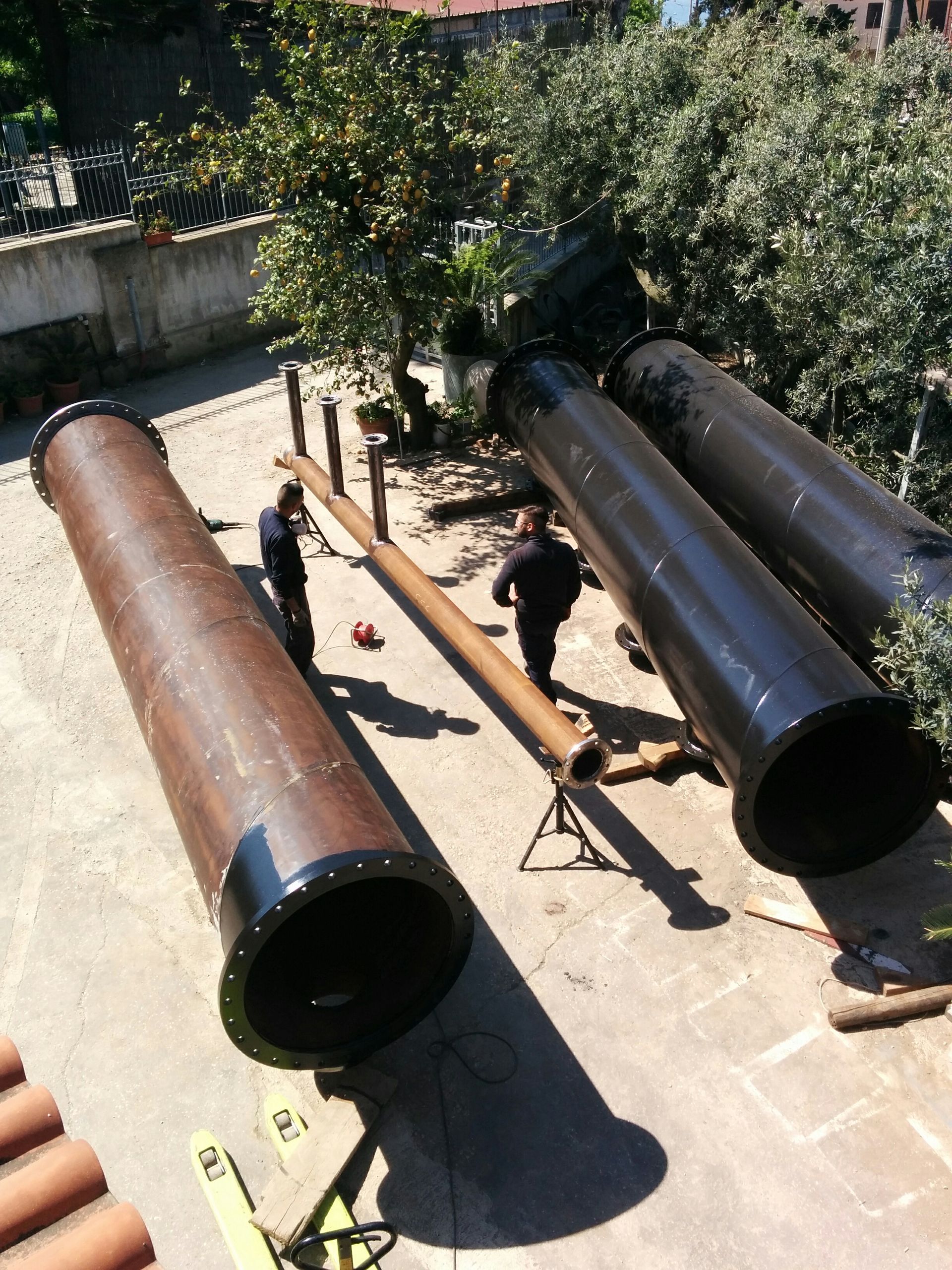 Un mucchio di tubi sono appoggiati a terra in un cortile