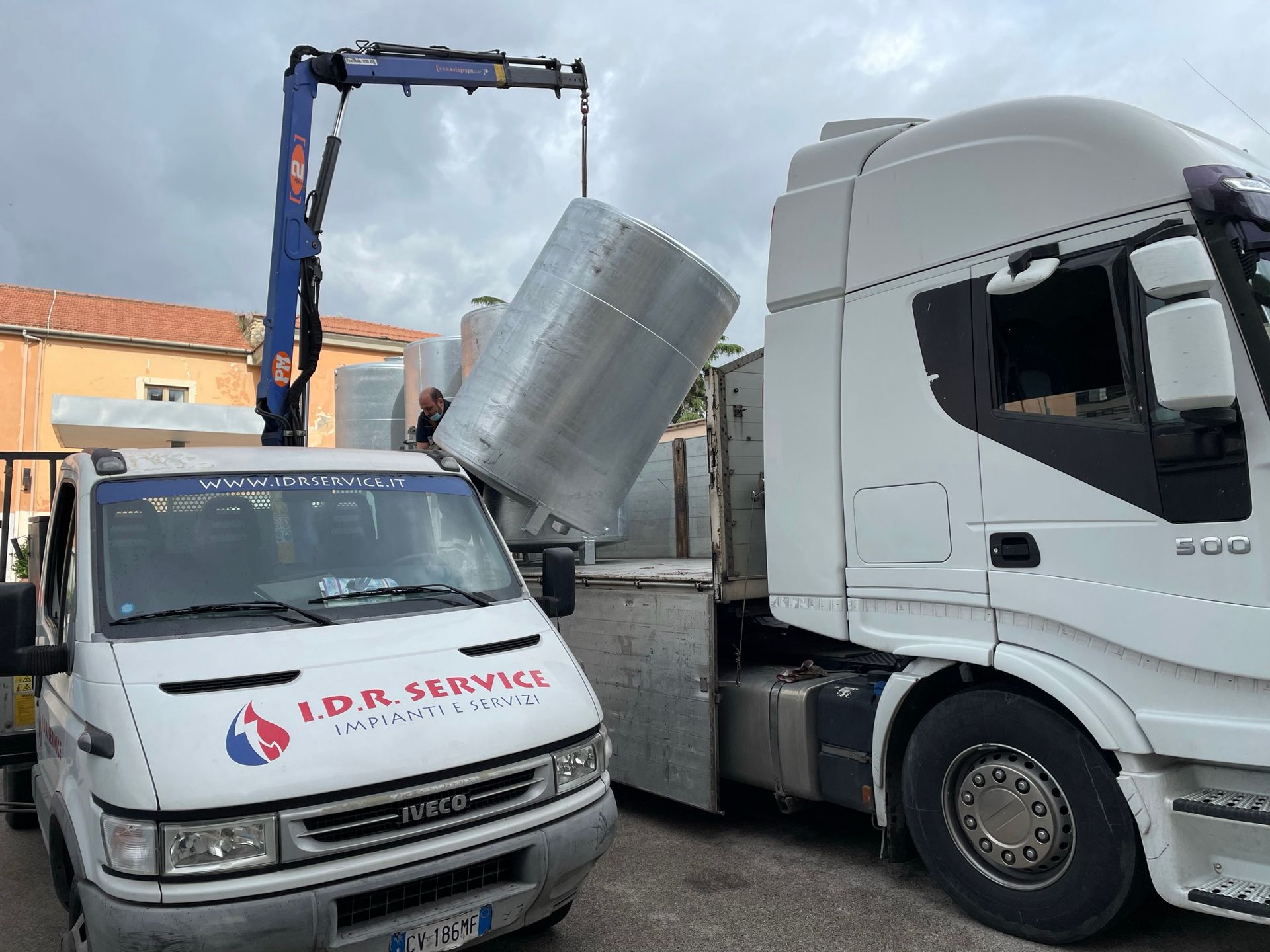 Un camion con una gru attaccata e un furgone che dice servizio idr