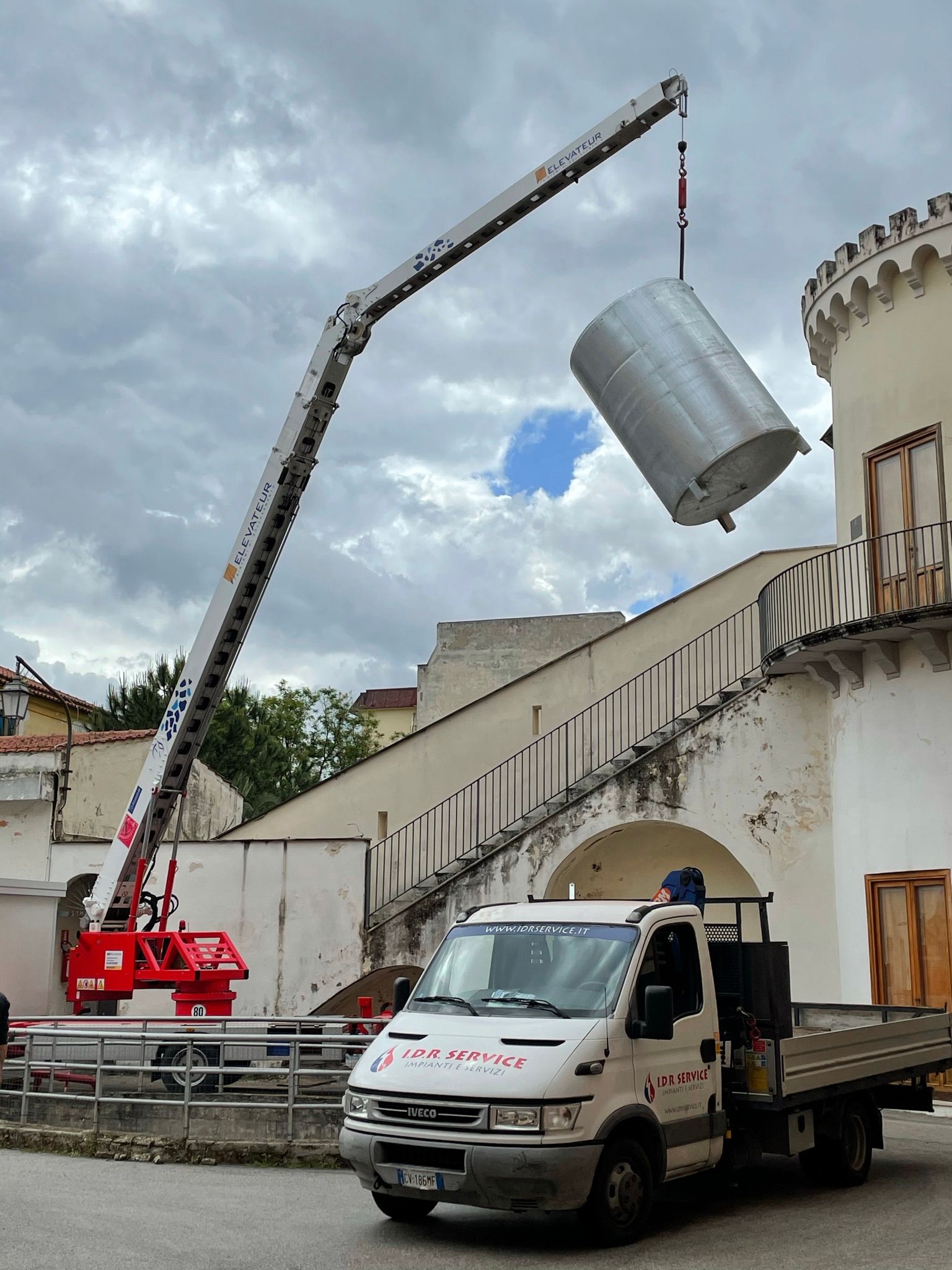 Un camion viene sollevato da una gru davanti a un edificio