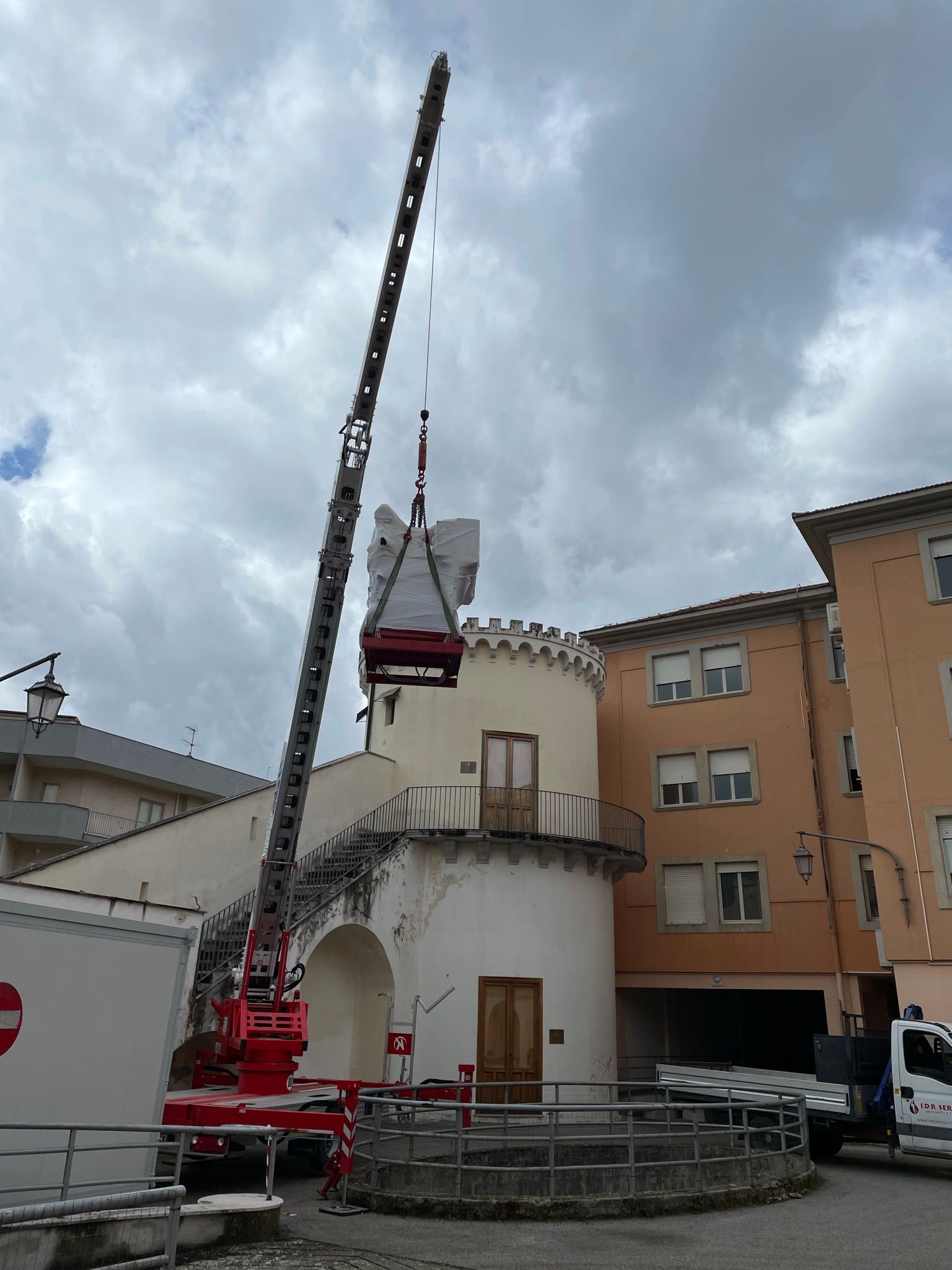 Una gru rossa sta sollevando un edificio di fronte a un edificio.