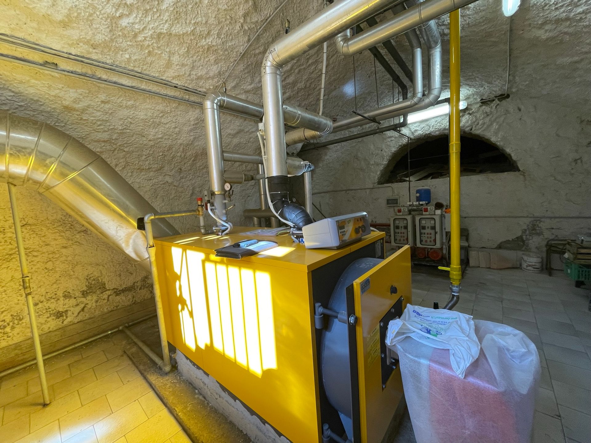 Una macchina gialla è parcheggiata in una stanza accanto a un bidone della spazzatura.