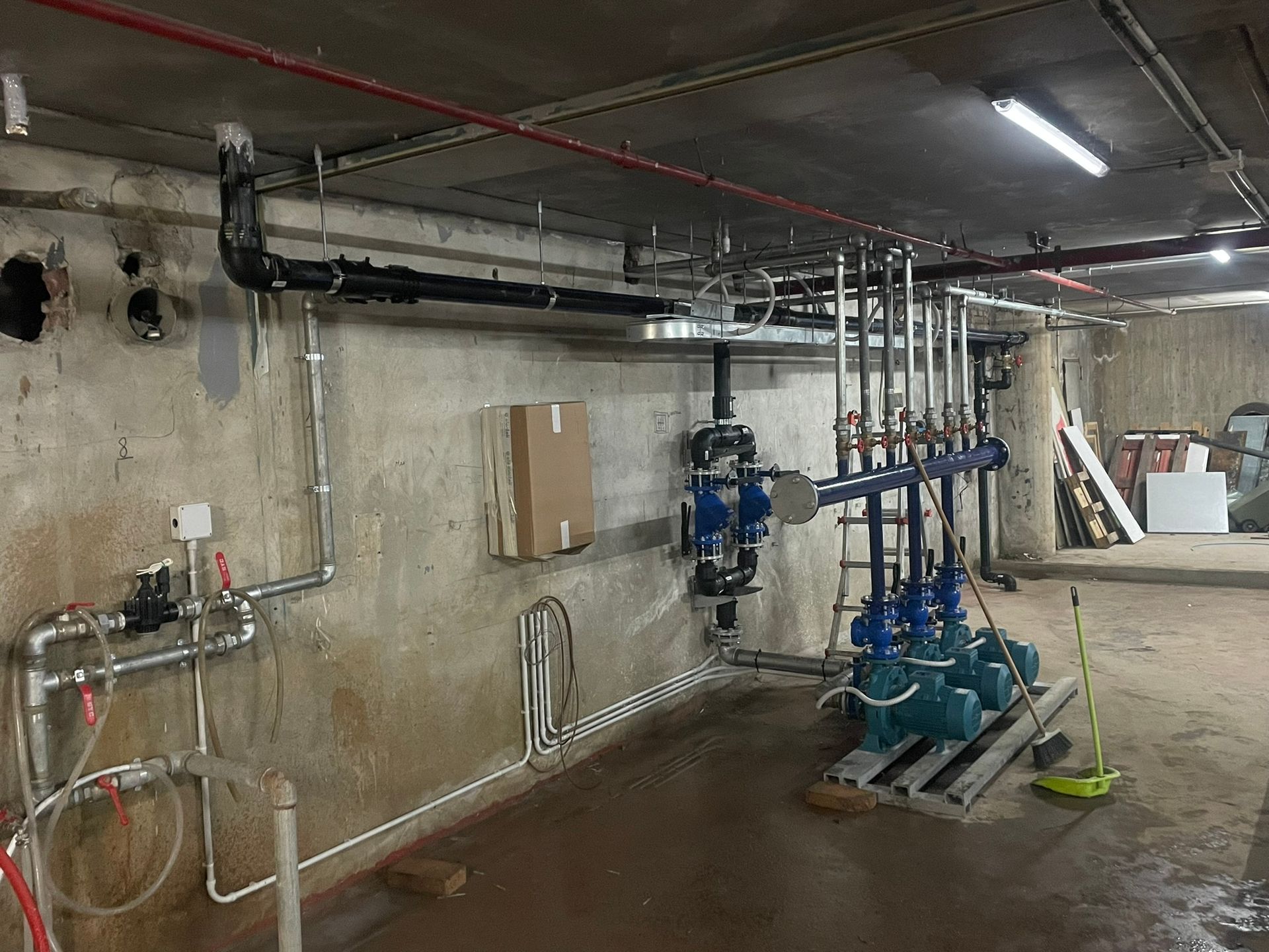 Una stanza con un sacco di tubi e una scatola sul muro.