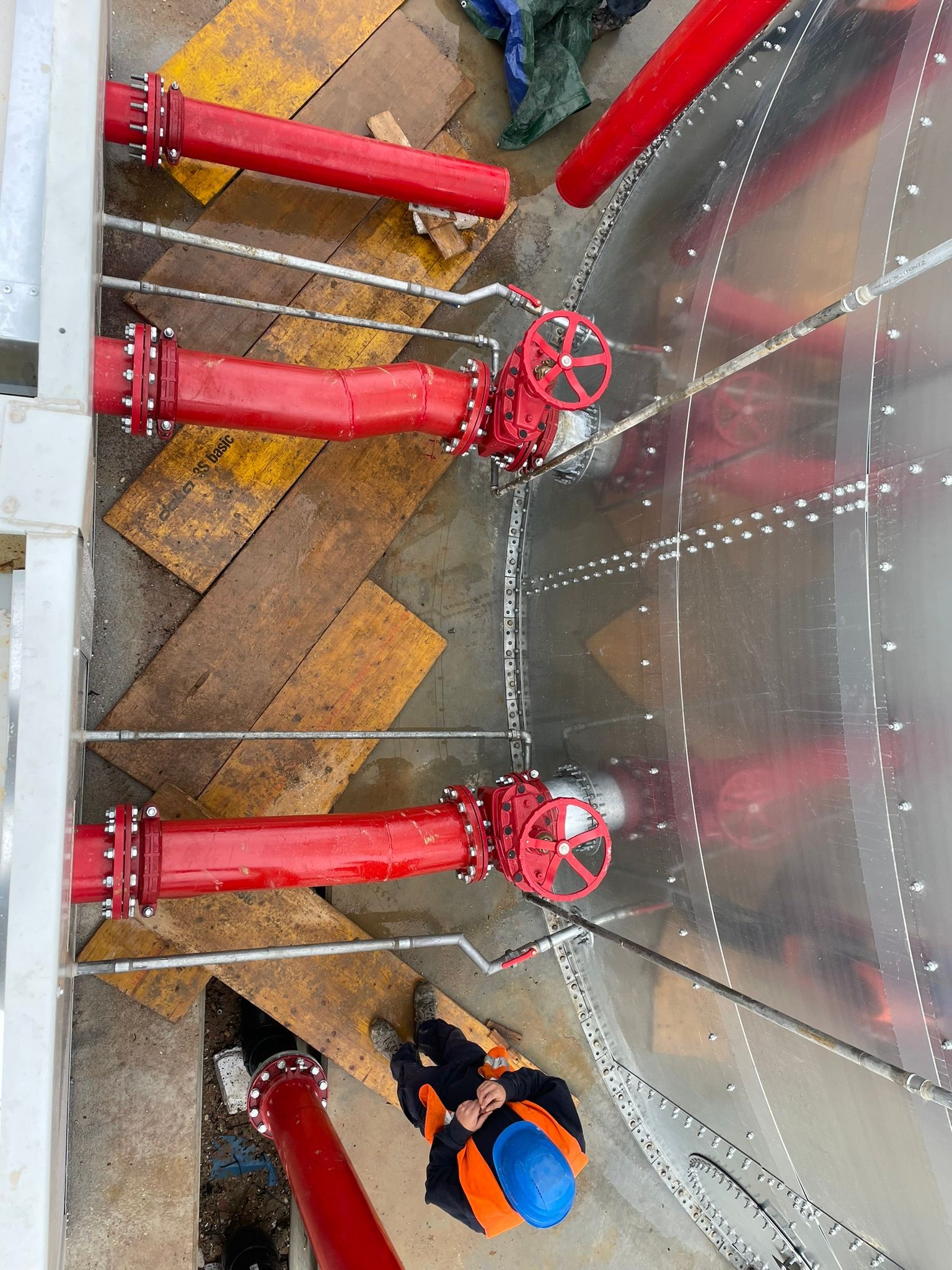 Un uomo è in piedi in una stanza con tubi e valvole rossi.