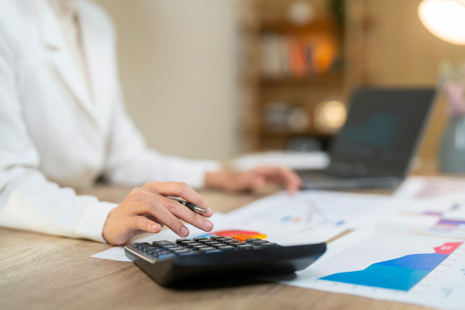 Person in white blazer uses a calculator