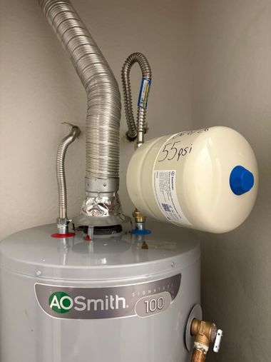 A.O. Smith water heater with silver vent pipe and white expansion tank mounted on top.