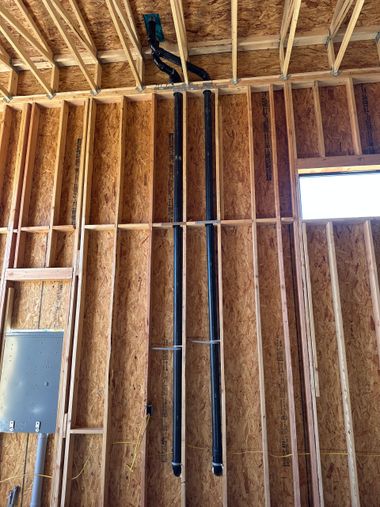 Unfinished interior wall framing with exposed wood studs, wiring, and a small window opening