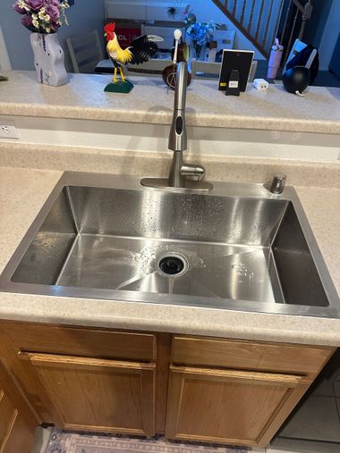 Stainless steel kitchen sink with gooseneck faucet and wooden cabinets below